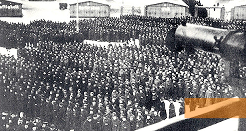 Bild:Oranienburg, um 1939, Zählappell im KZ Sachsenhausen, im Vordergrund Lauf des Maschinengewehrs auf »Turm A«, Gedenkstätte und Museum Sachsenhausen