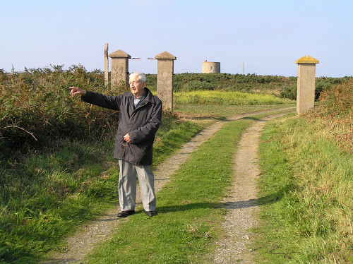 Alderney, 2008, Der Zeitzeuge Sylwester Kukula vor dem ehemaligen Eingangstor des Lagers Sylt, Yolanta Boot
