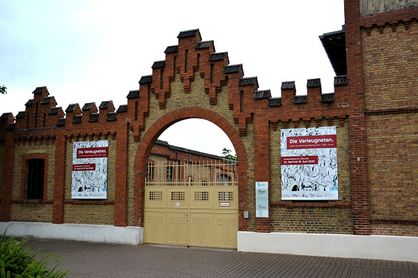 Osthofen, 2026, Entrance gate to the former camp featuring a poster for the travelling exhibition »The Disavowed«, Stiftung Denkmal